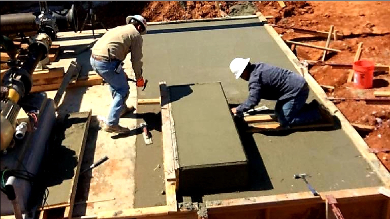 2 workers finishing a concrete slab poured by W5 Construction for a compressor & pump station